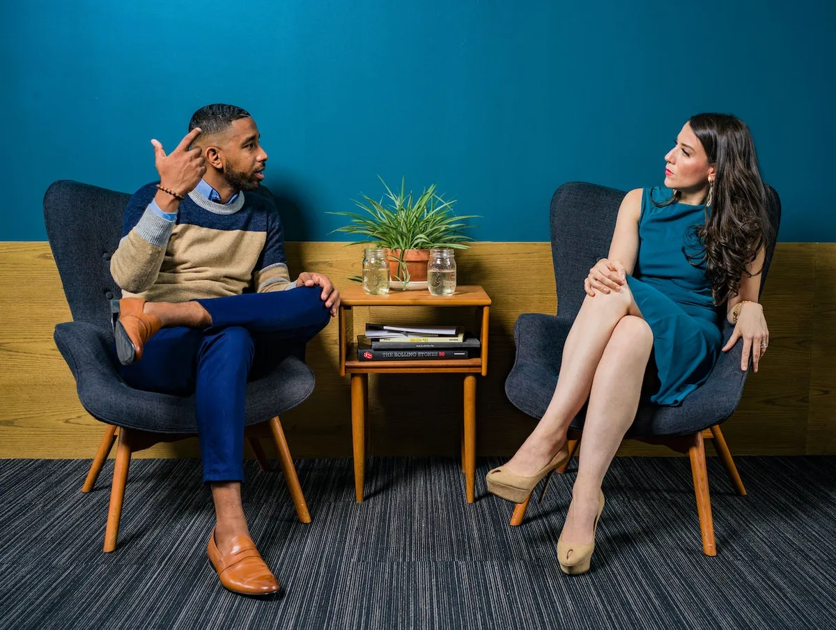 A man and a woman in conversation, seated in armchairs
