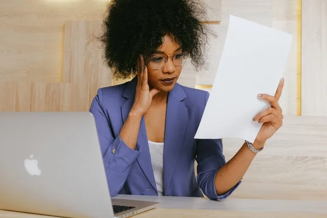 Woman in blue blazer holding white paper