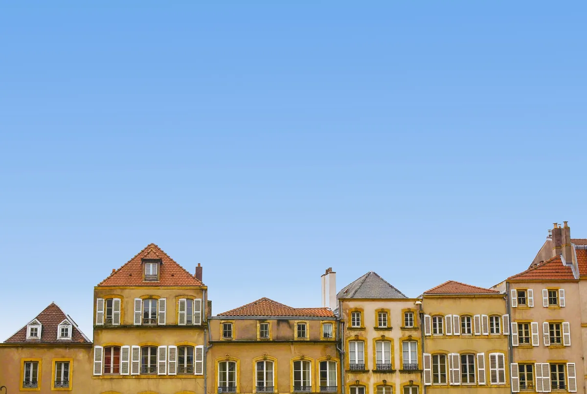 A row of older multi-story residential buildings under a blue sky