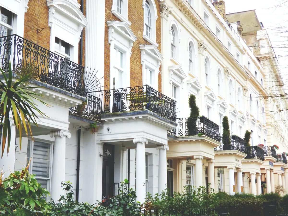 A row of white and brick multi-unit townhouse buildings with balconies
