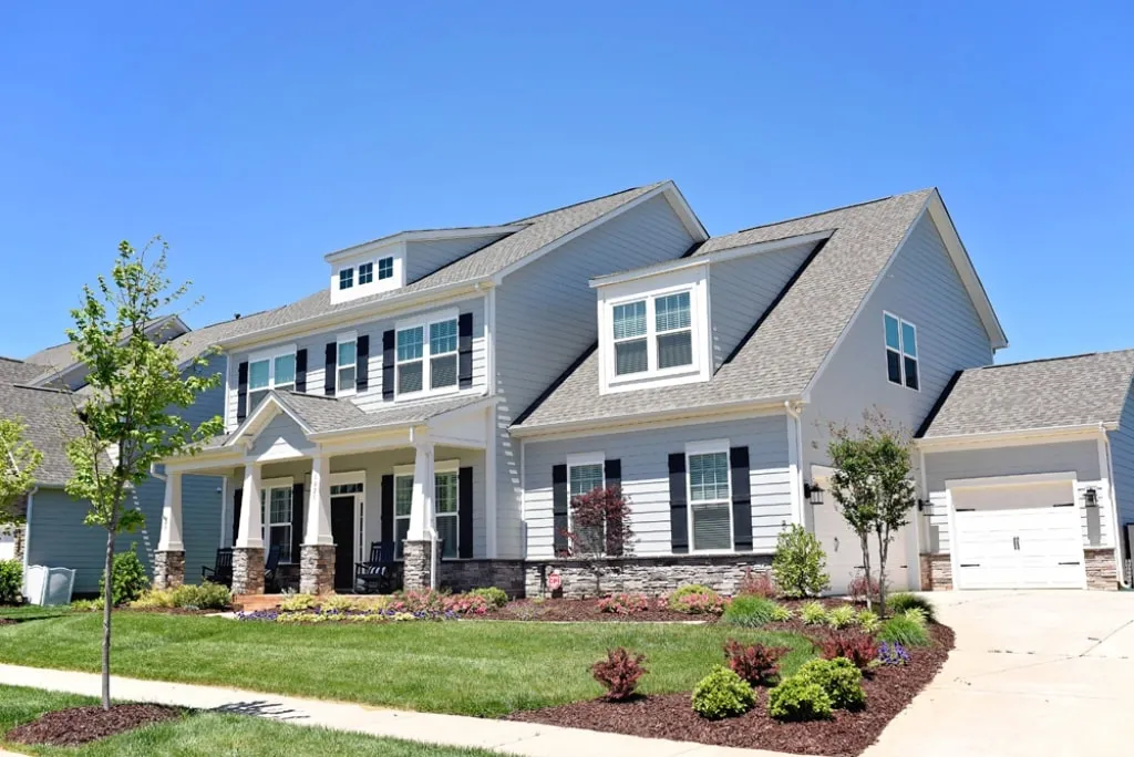 A two-story suburban home with a front lawn and landscaped garden