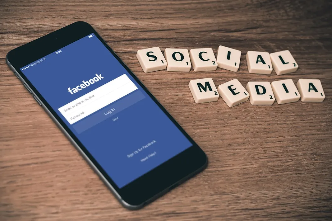 A smartphone showing a social media login next to scrabble tiles