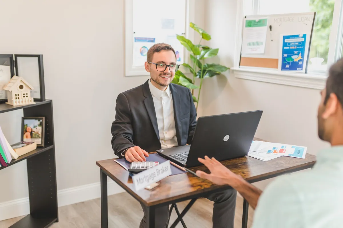A mortgage broker sitting across the desk from a homebuyer who wants a loan