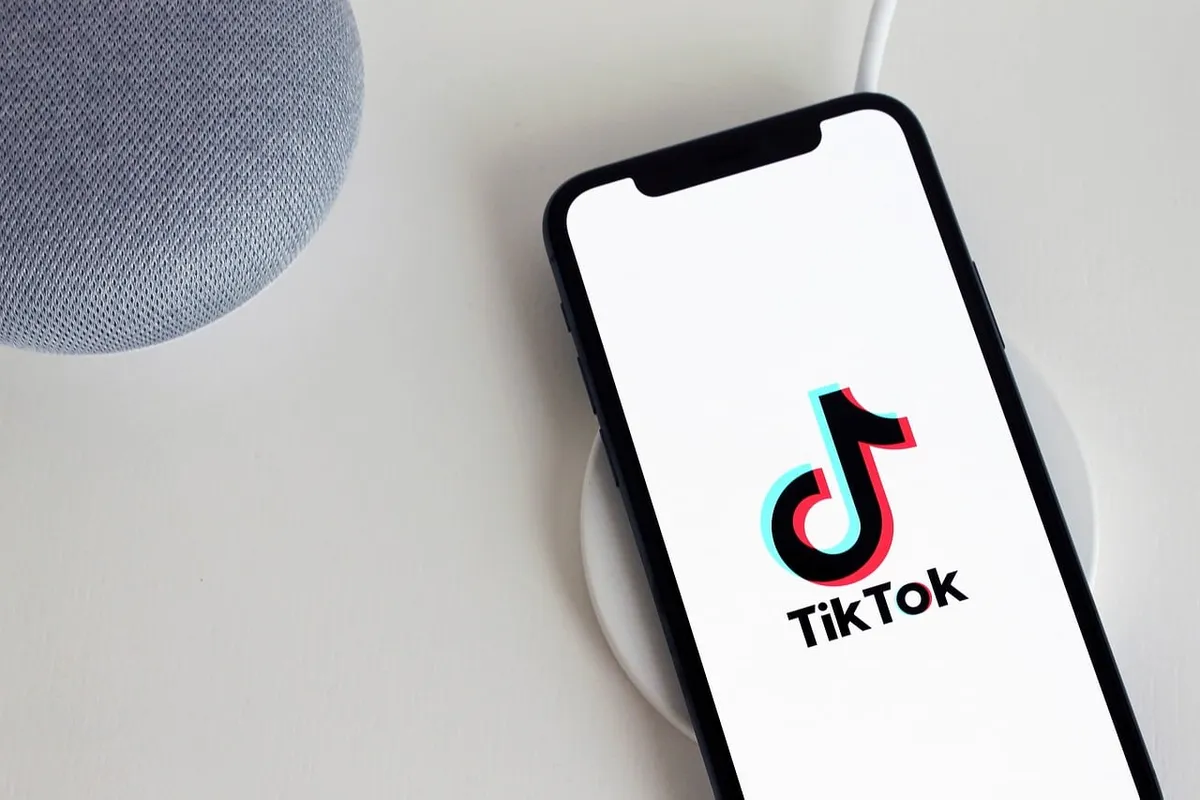 A smartphone showing the TikTok logo on a white desk