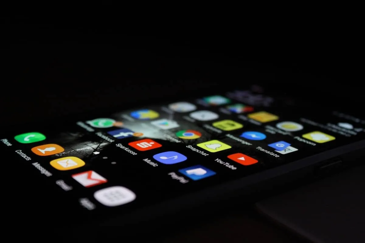 A smartphone home screen full of app icons, lit up in a dark room
