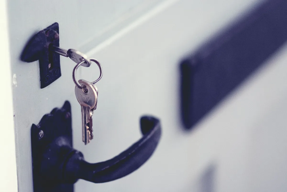 A key in the lock of a pale gray front door