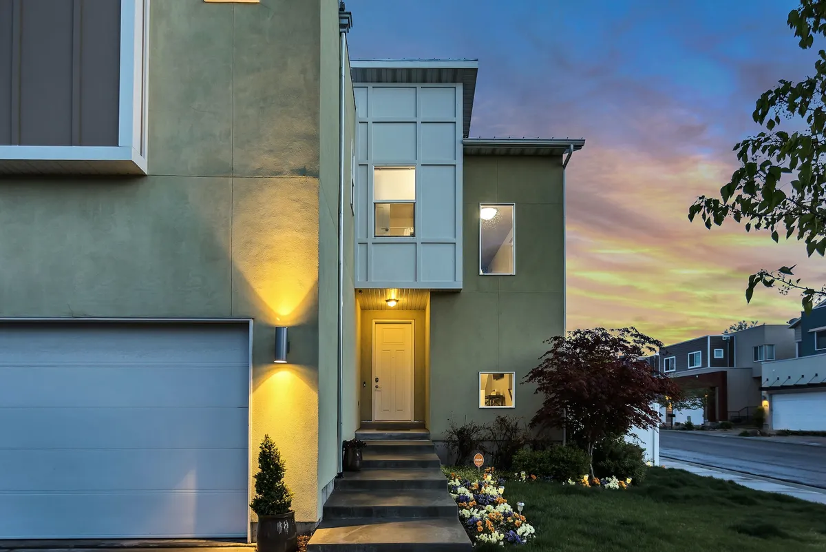 The front of a modern two-story house at dusk, with porch lights on