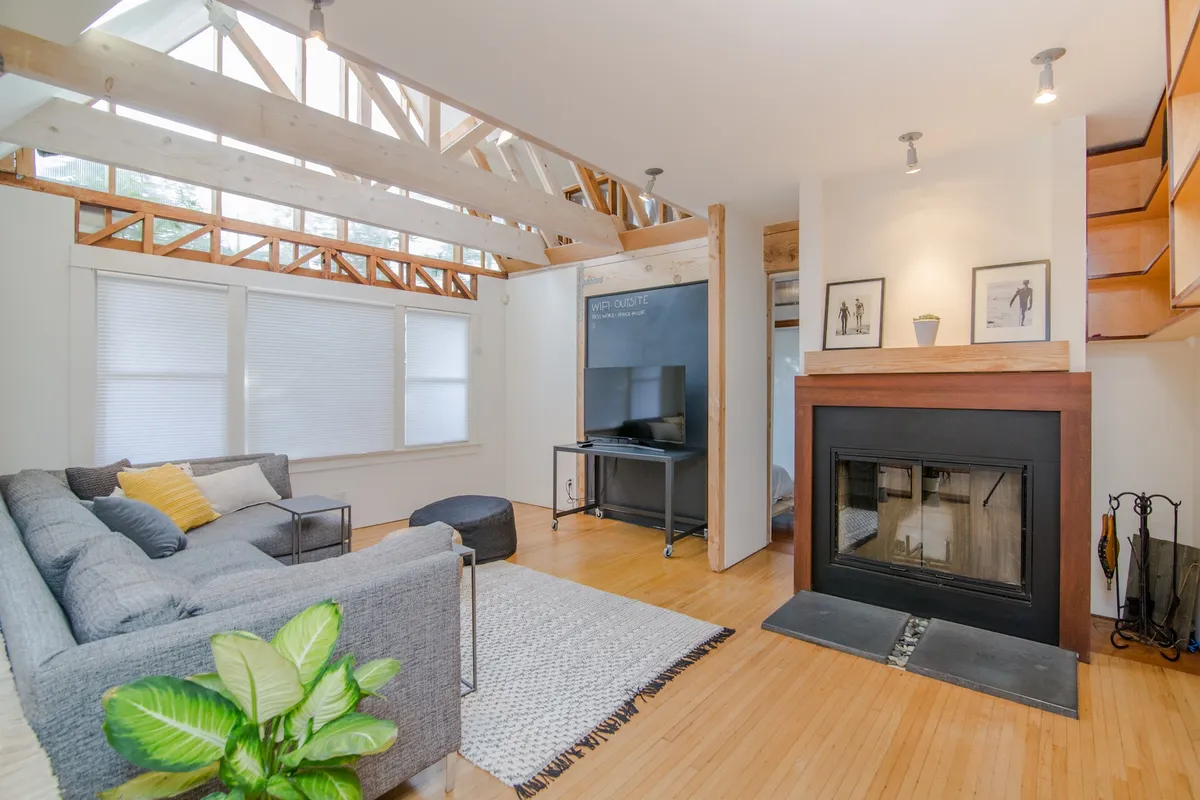 Bright open-plan living room with a fireplace and wooden ceiling beams
