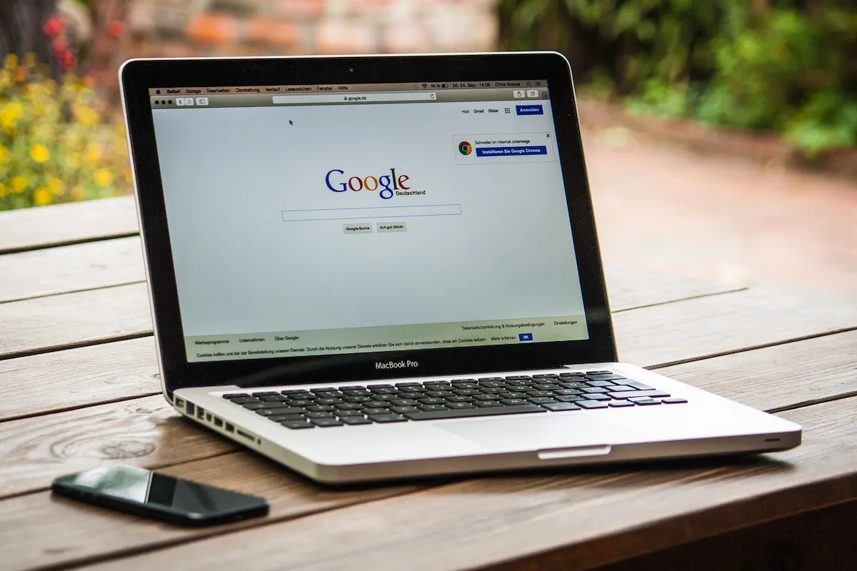 Smartphone and laptop open on the Google homepage.
