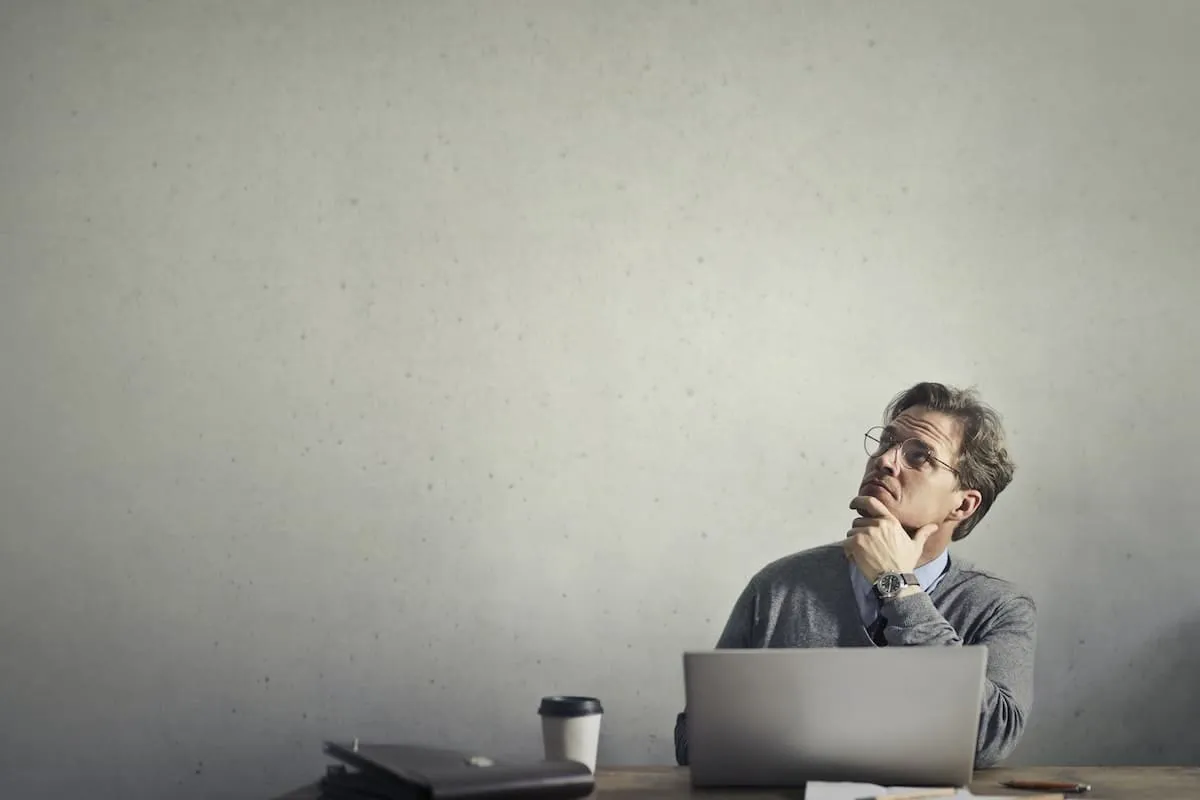 Real estate professional behind a laptop and thinking.