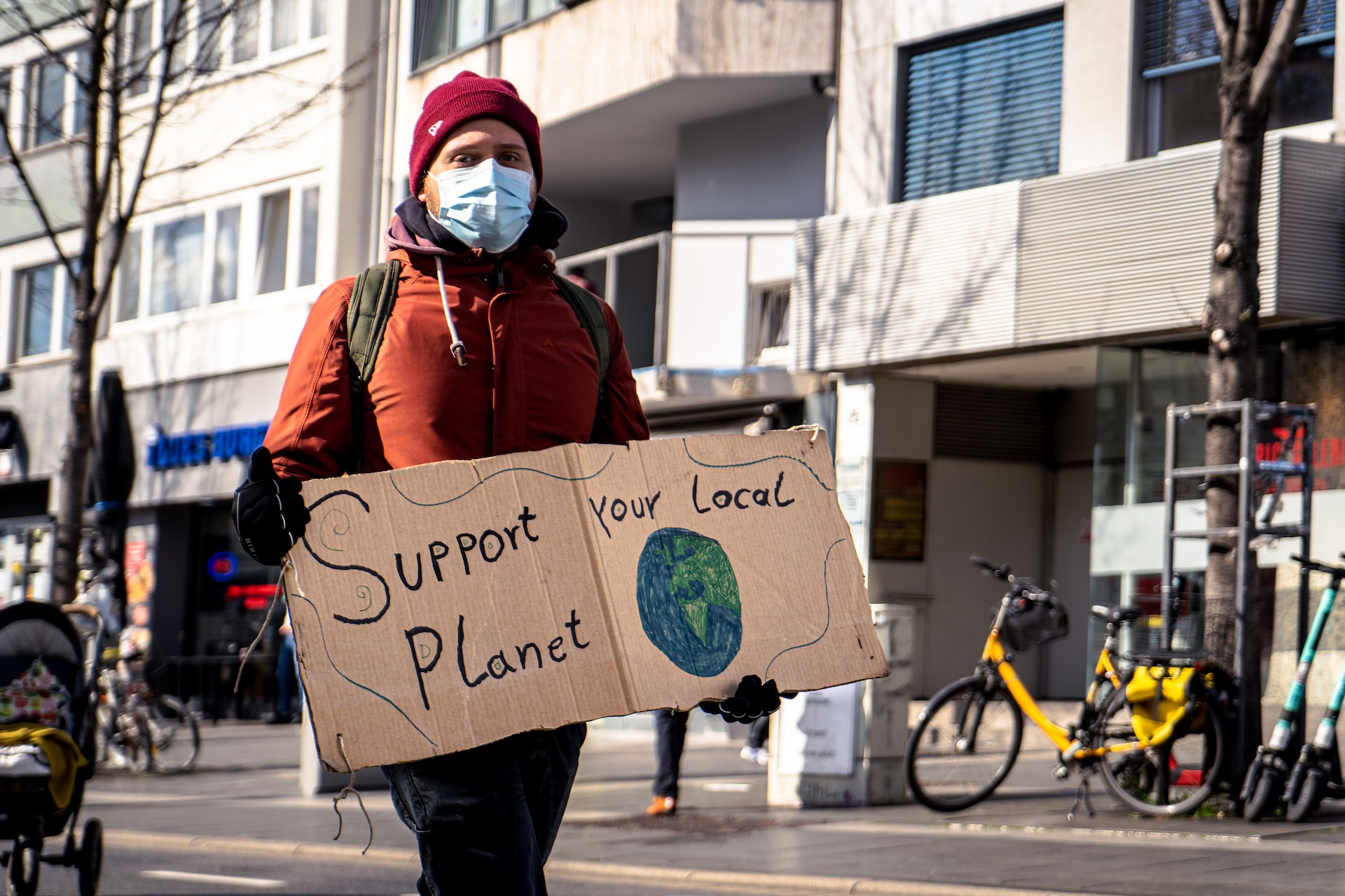 Man encouraging sustainable business practices with a sign stating Support your local planet.