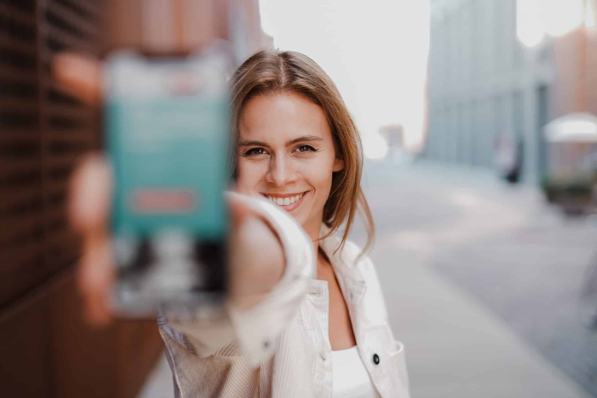 Smiling woman showing her mobile phone to the camera.